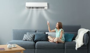 Young,Woman,Switching,On,Air,Conditioner,While,Sitting,On,Sofa hurda klima